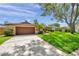 Single-story home features a well-manicured lawn and large garage with brown door at 11245 Bella Loma Dr, Largo, FL 33774
