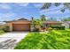 Well-maintained single-story home with a large garage, small palm trees and colorful plants at 11245 Bella Loma Dr, Largo, FL 33774