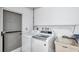 Bright laundry room with modern, front load washer and dryer plus utility sink and door to the exterior at 11245 Bella Loma Dr, Largo, FL 33774