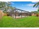 Backyard view of a screened-in pool area with a small shed in the distance and green grass in the foreground at 11245 Bella Loma Dr, Largo, FL 33774