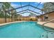 Screened-in pool features cool blue water, dark frame and chairs for enjoying the outdoors at 11245 Bella Loma Dr, Largo, FL 33774