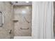 A shower with tile surround and safety grab bars, featuring an adjustable shower head and a built-in shelf at 11245 Bella Loma Dr, Largo, FL 33774