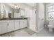 Bright bathroom featuring double vanity, glass-enclosed shower, and neutral tile flooring at 13019 Wildflower Meadow Dr, Riverview, FL 33579