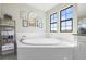 Elegant bathroom with a bright soaking tub beneath large windows, adorned with floral decor at 13019 Wildflower Meadow Dr, Riverview, FL 33579