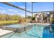 Inviting pool and spa with a stone fireplace, surrounded by lush greenery, in a screened-in lanai at 13019 Wildflower Meadow Dr, Riverview, FL 33579