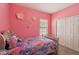 This cozy pink bedroom is perfect for a , complete with a bed with colorful sheets and closet doors at 13128 Foxtail Fern Dr, Riverview, FL 33579