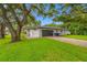 Residential house featuring a garage, a brick-paved driveway, a green lawn, and large trees at 1641 Jeffords St, Clearwater, FL 33756