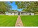Charming one-story home features a lush lawn, stone walkway, and inviting entrance with large shade trees at 1641 Jeffords St, Clearwater, FL 33756