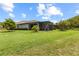 Spacious backyard with a screened lanai, lush green grass and mature trees on a sunny day at 16898 Balance Cv, Land O Lakes, FL 34638