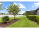 Landscaped backyard with manicured lawn, lush plantings, and a peaceful view of the adjacent lake at 16898 Balance Cv, Land O Lakes, FL 34638