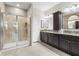 Bathroom featuring a glass shower and a dual sink vanity with dark cabinets at 16898 Balance Cv, Land O Lakes, FL 34638