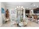 Elegant dining area featuring a glass table, ornate chandelier, and open kitchen access at 16898 Balance Cv, Land O Lakes, FL 34638