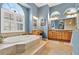 Luxurious bathroom with a soaking tub, dual vanities, arched windows, and recessed lighting for a spa-like feel at 17203 Talence Ct, Tampa, FL 33647
