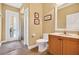 Bright bathroom featuring wood floors, a vanity with sink, toilet, walk-in shower, and a door to the outside at 17203 Talence Ct, Tampa, FL 33647