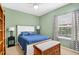 Light-filled bedroom with a queen-size bed, ceiling fan, wooden bookshelf, and a window with patterned curtains at 17203 Talence Ct, Tampa, FL 33647