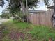 Side yard with wooden fence, overgrown with weeds, grass, and foliage at 1835 15Th S Ave, St Petersburg, FL 33712