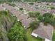 Aerial view of several homes with well-manicured lawns and neutral-toned roofs surrounded by mature trees at 19204 Weymouth Dr, Land O Lakes, FL 34638