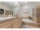 Well-lit bathroom featuring dual sinks, a soaking tub, and a glass-enclosed shower at 19204 Weymouth Dr, Land O Lakes, FL 34638