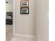Hallway leading to a bedroom with tan tile floors and Gathering photos on the wall at 19204 Weymouth Dr, Land O Lakes, FL 34638