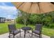 Seating arrangement on a patio with umbrella and a pond view in the background surrounded by lush trees at 19204 Weymouth Dr, Land O Lakes, FL 34638