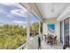 Cozy screened balcony with seating offers a peaceful spot to enjoy the surrounding treetop views and fresh air at 204 Haven Beach Ct, Indian Rocks Beach, FL 33785