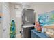 Functional laundry room with stacked washer and dryer, storage, and beach themed decor at 204 Haven Beach Ct, Indian Rocks Beach, FL 33785