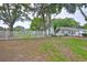 Spacious backyard with a white picket fence, mature trees, and lush greenery at 215 Claire Dr, Seffner, FL 33584