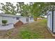 Backyard view features a brick accent, mature trees, storage shed, and well-maintained lawn at 215 Claire Dr, Seffner, FL 33584