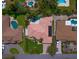 Aerial view of a house with a red tile roof surrounded by lush greenery, neighboring houses, and swimming pools at 307 Palmetto Ln, Largo, FL 33770