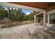 Inviting covered patio with stone pavers, lounge chairs, and a view of the lushly landscaped pool area at 307 Palmetto Ln, Largo, FL 33770