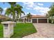Beautifully landscaped home with mature palm trees, a paver driveway, and a well-maintained lawn at 307 Palmetto Ln, Largo, FL 33770
