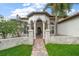 Beautiful home entrance with a brick pathway, stone columns, and a landscaped yard at 307 Palmetto Ln, Largo, FL 33770