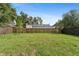 Large backyard featuring a well-maintained lawn and a wooden fence, surrounded by mature trees at 3105 E Osborne Ave, Tampa, FL 33610