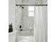 Updated bathroom featuring a tub and shower with marble tile, black hardware, and a window at 3105 E Osborne Ave, Tampa, FL 33610