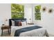 Cozy bedroom featuring a comfortable bed, stylish decor, and plenty of natural light from two windows at 3105 E Osborne Ave, Tampa, FL 33610