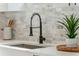 Bright kitchen sink with black faucet, stone backsplash, and stainless steel basin at 3105 E Osborne Ave, Tampa, FL 33610