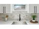 Kitchen sink with stainless steel basin, black faucet, stone backsplash, and window view at 3105 E Osborne Ave, Tampa, FL 33610