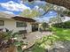 Landscaped backyard featuring stone pavers, patio furniture, umbrella, a lush lawn and mature trees at 3504 Wedge Way, New Port Richey, FL 34655