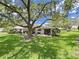 A serene backyard featuring lush greenery, a mature shade tree, and a patio area for relaxation at 3504 Wedge Way, New Port Richey, FL 34655