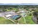 Aerial view of clubhouse featuring tennis courts, parking, pool, and well-manicured green spaces near a pond at 3504 Wedge Way, New Port Richey, FL 34655