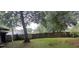 Large backyard with a wood fence, shade trees, and grass at 3513 Danny Bryan Blvd, Tampa, FL 33619