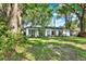 View of the home nestled among mature trees, boasting a green lawn, and classic architectural details at 3615 Greatwood Ct, Land O Lakes, FL 34639