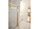 Bathroom featuring a glass shower with gold trim, white tiled floor and a view to the bedroom at 38819 Otis Allen Rd, Zephyrhills, FL 33540