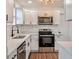 Modern kitchen features white cabinets, stainless steel appliances, quartz countertops, and a stylish faucet at 410 Virginia Ave, Madeira Beach, FL 33708