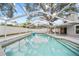Backyard with a screened-in pool, patio area, lush landscaping, and mature trees at 4509 Grainary Ave, Tampa, FL 33624