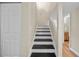Staircase featuring black steps, white risers and trim, and a view of the hallway and a bedroom at 4509 Grainary Ave, Tampa, FL 33624