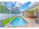 Sparkling in-ground pool inside the screened-in patio, with outside seating and lush green grass beyond the white fence at 4531 River Overlook Dr, Valrico, FL 33596