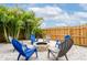 Landscaped backyard fire pit area with Adirondack chairs, a stone firepit, palm trees, and white gravel at 4916 Palmetto Point Dr, Palmetto, FL 34221