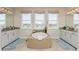 A luxurious bathroom with a large bathtub, white cabinets, and double sinks offer a serene retreat at 4973 Antiquity Way, Sarasota, FL 34240