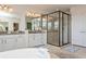 Bright bathroom featuring granite counters, tiled floors, and an elegant glass enclosed shower at 4973 Antiquity Way, Sarasota, FL 34240